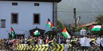 Os ciclistas passam por manifestantes com bandeiras da Palestina durante a etapa 13 da "Vuelta a Espana", em Cabezon de la Sal a L'angliru, Cantábria, Espanha em 5 de setembro de 2025.  Foto: REUTERS - PANKRA NIETO / RFI