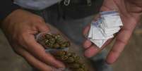 Traficante exibe pequenos pacotes de maconha e cocaína destinados à venda.  Foto: © JOAQUIN SARMIENTO / AFP / RFI