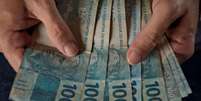 Mãos contando notas de cem reais  Foto: Getty Images / BBC News Brasil