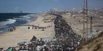 Palestinos, carregando os pertences que conseguiram levar consigo, movem-se em direção à parte norte da Faixa de Gaza pela Rua Rashid, que conecta o norte e o sul do enclave, na Cidade de Gaza  Foto: Khames Alrefi/Anadolu via Getty Images