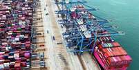 Vista aérea de um navio em um porto de contêineres com muitos contêineres no navio e também no lado do porto esperando para serem carregados  Foto: Getty Images / BBC News Brasil