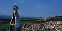 Uma estátua de 50 metros de altura de Nossa Senhora Aparecida, com a cidade de Aparecida ao fundo  Foto: AFP / BBC News Brasil
