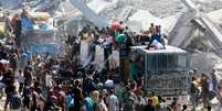 Palestinos recolhem alimentos em caminhões que entraram em Gaza, em Khan Younès, no sul da Faixa de Gaza, em 12 de outubro de 2025  Foto: REUTERS - Ramadan Abed / RFI