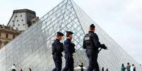 Policiais franceses caminham perto da Pirâmide de Vidro do Museu do Louvre, em Paris, França, em 27 de outubro de 2025.  Foto: © Abdul Saboor / Reuters / RFI