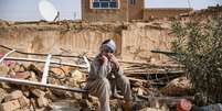 Um sobrevivente do terremoto no Afeganistão senta sobre os escombros de uma casa destruída em uma vila de Tashqurghan, no distrito de Khulm, província de Samangan  Foto: AFP - ATIF ARYAN / RFI