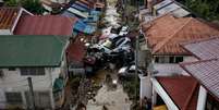 Uma imagem capturada por um drone mostra um homem atravessando uma rua lamacenta onde carros ficaram empilhados após serem arrastados pelas enchentes causadas pelo tufão Kalmaegi, que atingiu um bairro em Bacayan, na cidade de Cebu, nas Filipinas, em 5 de novembro de 2025.  Foto: REUTERS - Eloisa Lopez / RFI