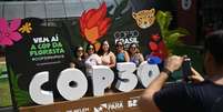 Turistas diante do símbolo da COP30 em Belém.  Foto: AFP - MAURO PIMENTEL / RFI