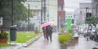 Pedestres se protegem da chuva em Venâncio Aires, no Rio Grande do Sul, nesta sexta-feira (7), durante passagem de um ciclone extratropical pela região. O estado está em alerta para grande volume de chuva e rajadas de vento.  Foto: LEANDRO OSÓRIO/ATO PRESS/ESTADÃO CONTEÚDO
