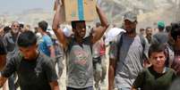 Homem palestino carrega caixa de comida obtida no ponto de passagem de Zikim, no norte da Faixa de Gaza, em 1º de agosto de 2025.  Foto: AFP - BASHAR TALEB / RFI