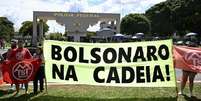 Membros do Movimento dos Trabalhadores Sem-Teto (MTST) exibem faixa diante da superintendência da Polícia Federal, em Brasília, onde o ex-presidente Jair Bolsonaro está preso preventivamente. Brasília, 22 de novembro de 2025.  Foto: AFP - EVARISTO SA / RFI