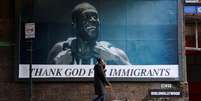 Uma pessoa passa por um outdoor com a imagem do rapper Stormzy, parte da campanha "Thank God For Immigrants" (Agradeça a Deus pelos Imigrantes) do grupo ativista Everyone Hates Elon, que celebra ícones imigrantes da cultura britânica, em Londres, Reino Unido, em 30 de outubro de 2025.  Foto: REUTERS - Hiba Kola / RFI