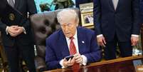Trump mexendo no telefone  Foto: Bloomberg via Getty Images / BBC News Brasil