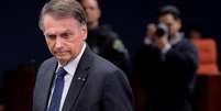 Bolsonaro com olhar sério, de terno e gravata, no STF; atrás, fotógrafos  Foto: Reuters / BBC News Brasil