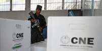 Um soldado diante de caixas contendo material eleitoral em um local de voto na capital Tegucigalpa, em 29 de novembro de 2025, à véspera das eleições.  Foto: AFP - MARVIN RECINOS / RFI