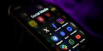 Telefone celular mostrando ícones de redes sociais e aplicativos de mensagens na tela  Foto: Getty Images / BBC News Brasil