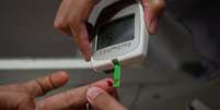 Foto mostra uma mulher fazendo um exame de sangue para verificar seu nível de açúcar em um laboratório Foto: AFP via Getty Images / BBC News Brasil