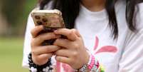 Uma jovem australiana fotografada com seu telefone em Sydney, Austrália, país onde a partir desta quarta-feira, 10 de dezembro de 2025, entrou em vigor a proibição do uso das redes sociais para menores de 16 anos.  Foto: © Hollie Adams / Reuters / RFI
