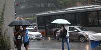 Pedestres se protegem da chuva que cai pela Avenida Paulista, regi&atilde;o centro-sul de S&atilde;o Paulo, neste s&aacute;bado (13). Foto: RENATO S. CERQUEIRA/ATO PRESS/ESTAD&Atilde;O CONTE&Uacute;DO