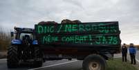 Membros da Associação dos Jovens Agricultores de Yvelines, na França, bloqueiam estrada com trator nesta terça-feira, nos arredores de Paris. 16 de dezembro de 2025  Foto: AFP - GEOFFROY VAN DER HASSELT / RFI