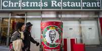 Japonesas passam pelo restaurante KFC em T&oacute;quio, onde a tradi&ccedil;&atilde;o na noite de Natal &eacute; comer frango frito.  Foto: AFP - YUICHI YAMAZAKI / RFI