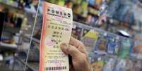 Um cliente segura um bilhete da loteria Powerball ap&oacute;s compr&aacute;-lo em Miami  Foto: Imagem de arquivo/Joe Raedle/Getty Images