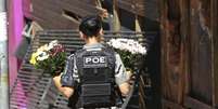 Uma policial de Santa Maria, no Rio Grande do Sul, leva flores para a frente da boate Kiss em homenagem &agrave;s v&iacute;timas do inc&ecirc;ndio no dia seguinte &agrave; trag&eacute;dia, em 28 de janeiro de 2013.  Foto: &copy; REUTERS/Edison Vara / RFI
