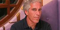 Jeffrey Epstein est&aacute; sentado e olha para a c&acirc;mera, vestindo uma camisa escura.  Foto: Getty Images / BBC News Brasil