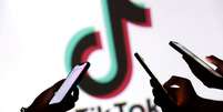Adolescentes posam com celulares em frente ao logo do TikTok, em imagem ilustrativa.  Foto: REUTERS - Dado Ruvic / RFI