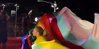 Daniela Mecury, bissexual e &iacute;cone do p&uacute;blico LGBTQIA+, se enrolou em uma bandeira do arco-&iacute;ris em protesto na Barra-Ondina, neste domingo, 15  Foto: Reprodu&ccedil;&atilde;o