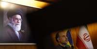 No detalhe, o embaixador do Irã no Brasil, Abdollah Nekounam, durante conversa com jornalistas, sob a imagem do aiatolá Ali Khamenei, morto em bombardeio americano e israelense  Foto: wilton junior/estadão / Estadão