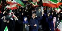 Iranianos agitam bandeiras nacionais e exibem fotos do novo L&iacute;der Supremo do pa&iacute;s, Mojtaba Khamenei, em um com&iacute;cio em Teer&atilde;.  Foto: EPA/Shutterstock / BBC News Brasil