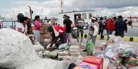 Ativistas da flotilha Nuestra Am&eacute;rica e autoridades cubanas descarregam ajuda humanit&aacute;ria do navio "Granma 2.0" no porto de Havana, em 24 de mar&ccedil;o de 2026.  Foto: AFP - JORGE LUIS BANOS / RFI