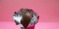 Um ovo de p&aacute;scoa com embalagem aberta em fundo rosa  Foto: Getty Images / BBC News Brasil