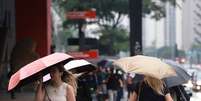 Pedestres caminham com guarda-chuva em tarde chuvosa na Avenida Paulista. Foto: Estad&atilde;o