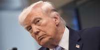 Donald Trump usando um broche com a bandeira americana. Ele olha fixamente para a frente.   Foto: EPA / BBC News Brasil