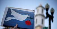 Manifestante segura uma placa com uma pomba da paz pr&oacute;ximo &agrave; Casa Branca, nos EUA, ap&oacute;s an&uacute;ncio de cessar-fogo  Foto: Alex Wong/Getty Images