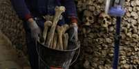 Um oper&aacute;rio transporta ossos humanos em um balde dentro das Catacumbas de Paris, em 24 de mar&ccedil;o de 2026, durante obras de restaura&ccedil;&atilde;o do monumento parisiense.  Foto: &copy; Kenzo Tribouillard / AFP / RFI