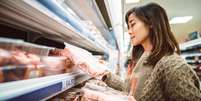 Mulher observa pacotes de frango no supermercado  Foto: Getty Images / BBC News Brasil