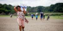 Mulher carrega garraf&otilde;es de &aacute;gua em terreno &aacute;rido no Brasil durante uma onda de calor Foto: Reuters / BBC News Brasil