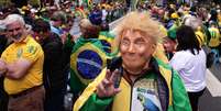 Um apoiador do ex-presidente Jair Bolsonaro usa uma máscara do presidente dos EUA, Donald Trump, durante uma manifestação que exige anistia para os presos pela suposta tentativa de golpe de 2023, em São Paulo, em 6 de abril de 2025.  Foto: RFI