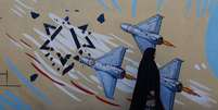 Iraniana caminha ao lado de mural anti-Israel em rua de Teerã
 18 de maio de 2026    Majid Asgaripour/WANA via REUTERS  Foto: Reuters