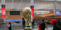 Passageiros passam por r&eacute;plica gigante do trof&eacute;u da Copa do Mundo no Aeroporto Internacional da Cidade do M&eacute;xico 
 18 de maio de 2026    REUTERS/Henry Romero  Foto: Reuters