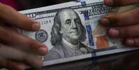 Um funcionário segura notas de dólar americano em uma casa de câmbio em Jacarta, na Indonésia (REUTERS/Willy Kurniawan)  Foto: Reuters