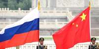 Militares seguram bandeiras da R&uacute;ssia e da China durante viagem de Putin a Xi  Foto: ANSA / Ansa - Brasil