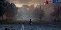 Uma mulher caminha por uma rua coberta de destroços após um ataque noturno russo com mísseis e drones, em meio à ofensiva da Rússia contra a Ucrânia, em Kiev, Ucrânia, em 24 de maio de 2026.  Foto: REUTERS - Thomas Peter / RFI