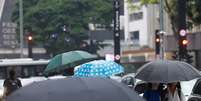 Pedestres caminham com guarda-chuva na Av. Paulista Foto: Daniel Teixeira/Estad&atilde;o / Estad&atilde;o