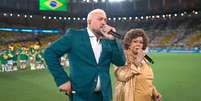 Belo e Alcione cantam o hino nacional brasileiro durante jogo do Brasil no Maracan&atilde;.  Foto: Reprodu&ccedil;&atilde;o de 'Brasil x Panam&aacute;' (2026)/TV Globo / Estad&atilde;o
