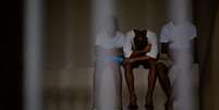 Imagem de meninos sentados presos, sem que o rosto deles apare&ccedil;am.   Foto: MAURO PIMENTEL/AFP via Getty Images / BBC News Brasil