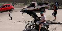 Um homem de motocicleta passa por estrada danificada ap&oacute;s terremotos atingirem a Venezuela  Foto: Reuters / BBC News Brasil