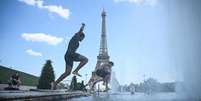 Pessoas mergulham na Fonte do Trocad&eacute;ro, perto da Torre Eiffel, durante uma onda de calor em Paris, em 22 de junho de 2026.  Foto: RFI